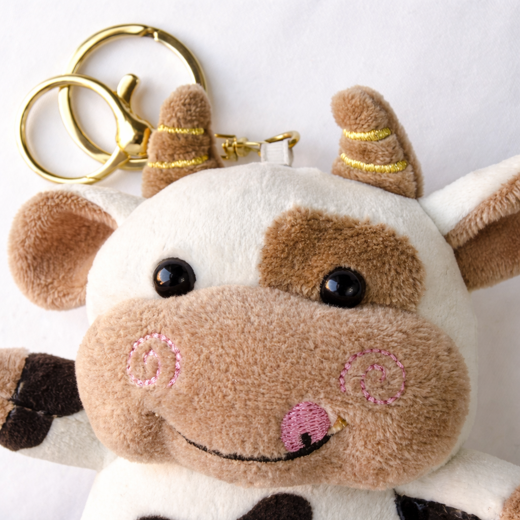 Givana cute plush cow keychain with golden clasp, soft stuffed animal accessory for keys or bags featuring a cute cow design.